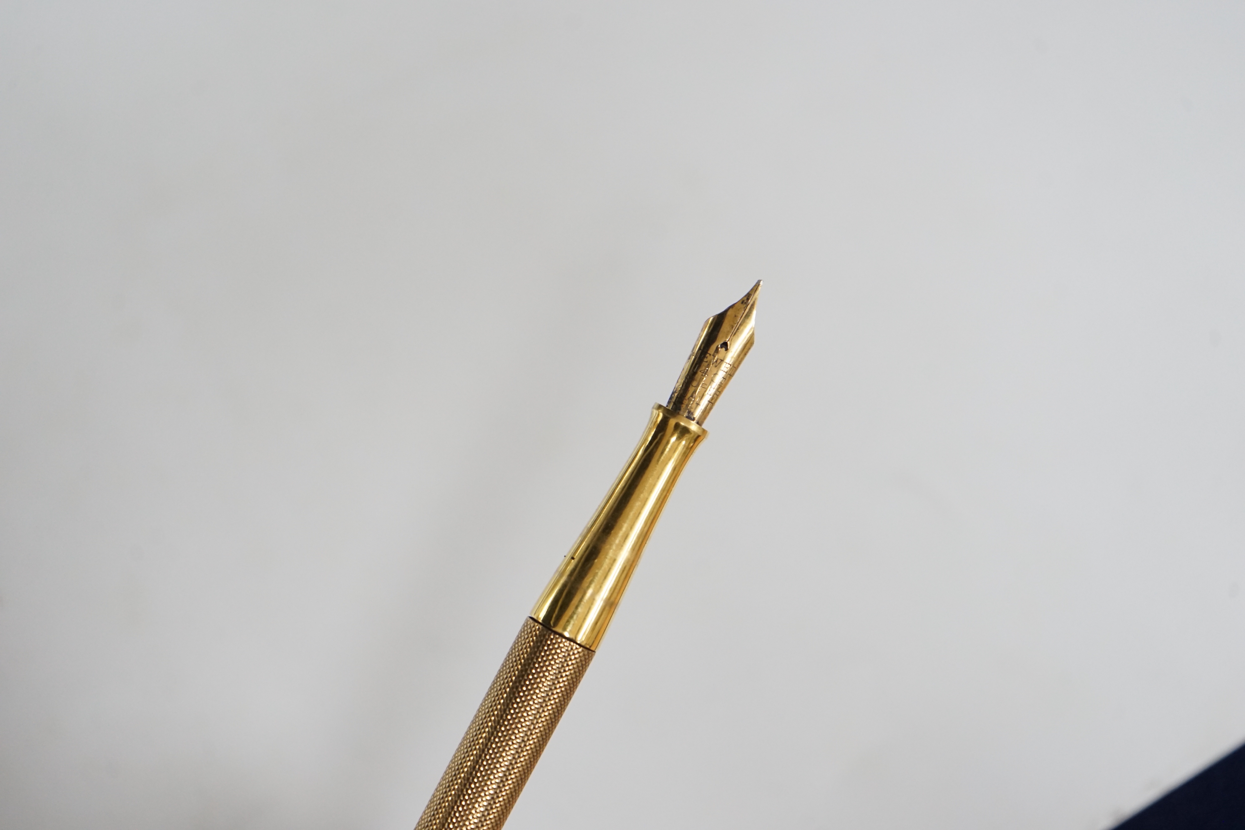 A George V engine turned 9ct. gold combination fountain pen and pencil, with holder (once attached to a stand), maker F.D.W. London, 1935, 20.4cm.